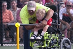 Volunteer assisting physically challenged little girl up to bat at the Joe Nuxhall Miracle League for baseball