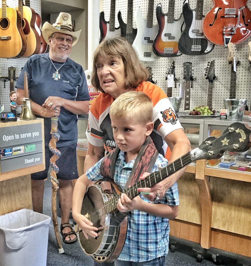 Young man getting his first experience as a banjo picker at the August 31, 2019 Grand Opening of Vernon McIntyre's Famous Old Time Music Company